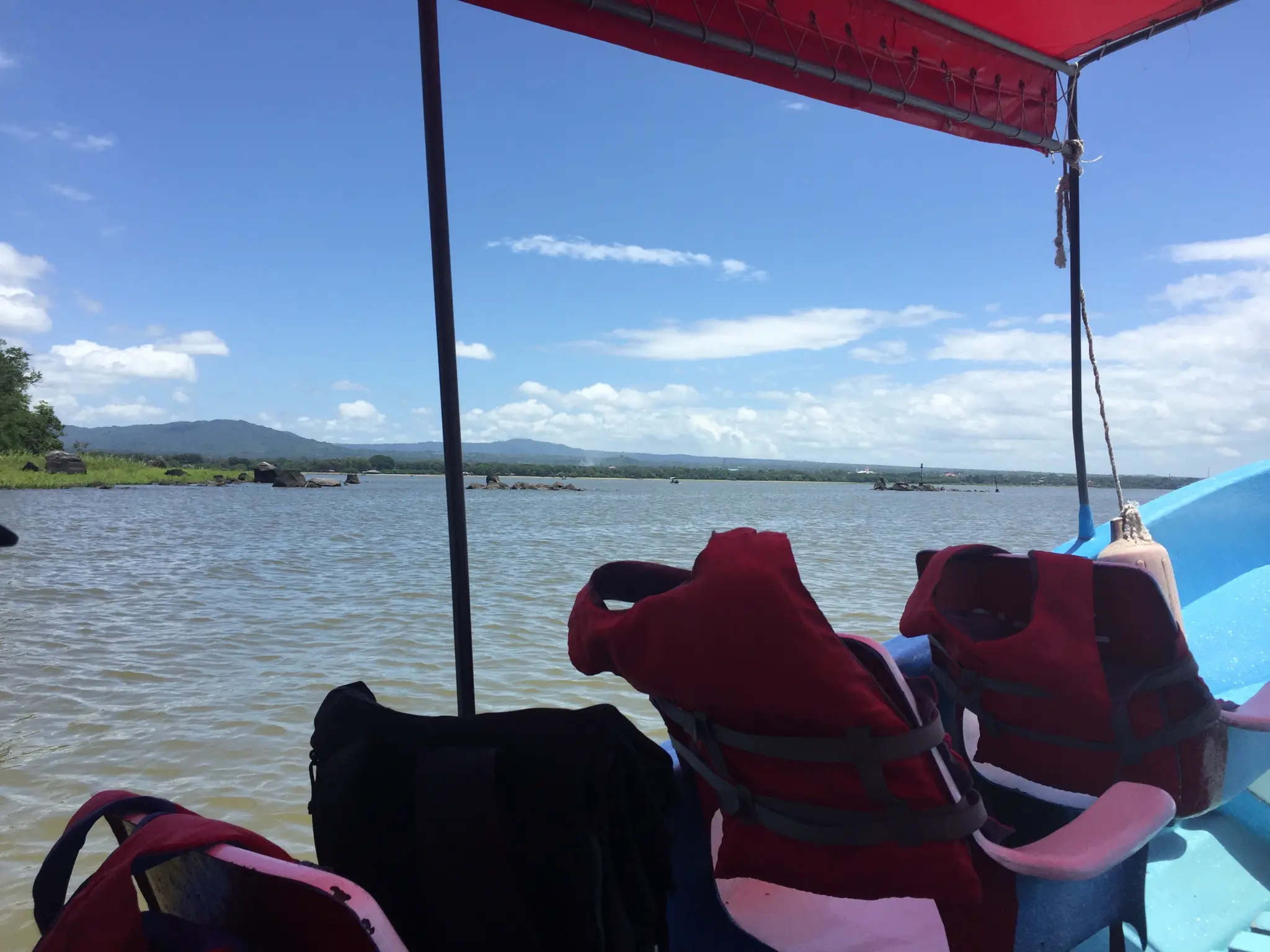 Boat tour on Lake Nicaragua heading toward Ometepe Island — red life jackets, blue boat, volcanic mountains in the distance