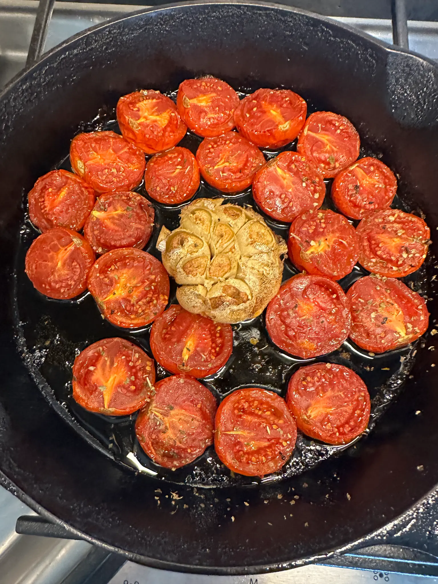 Roasted Campari tomatoes and whole roasted garlic head in a cast iron skillet