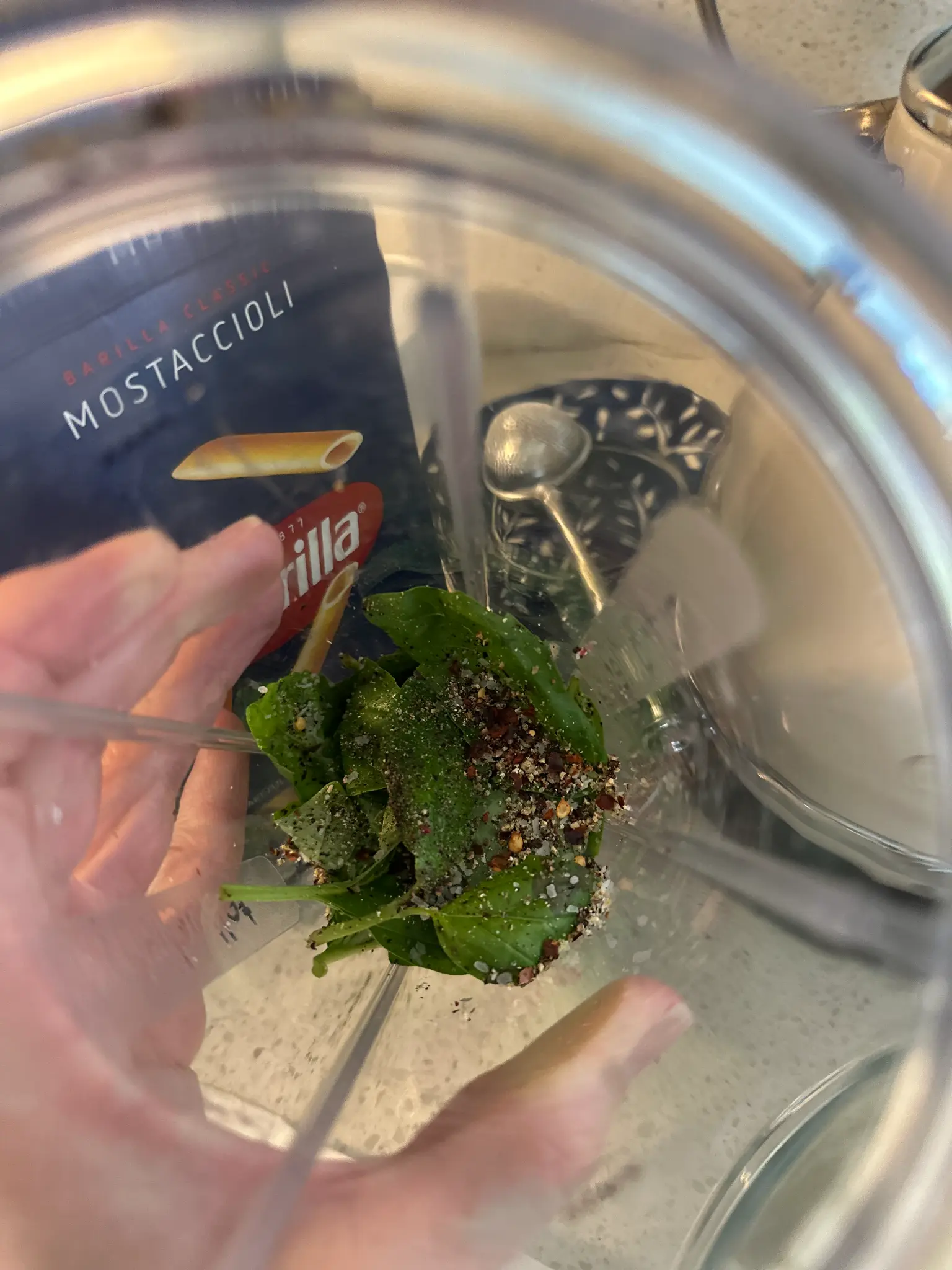 Fresh basil leaves, red chili flakes, salt and pepper in the blender ready to be blended with roasted tomatoes
