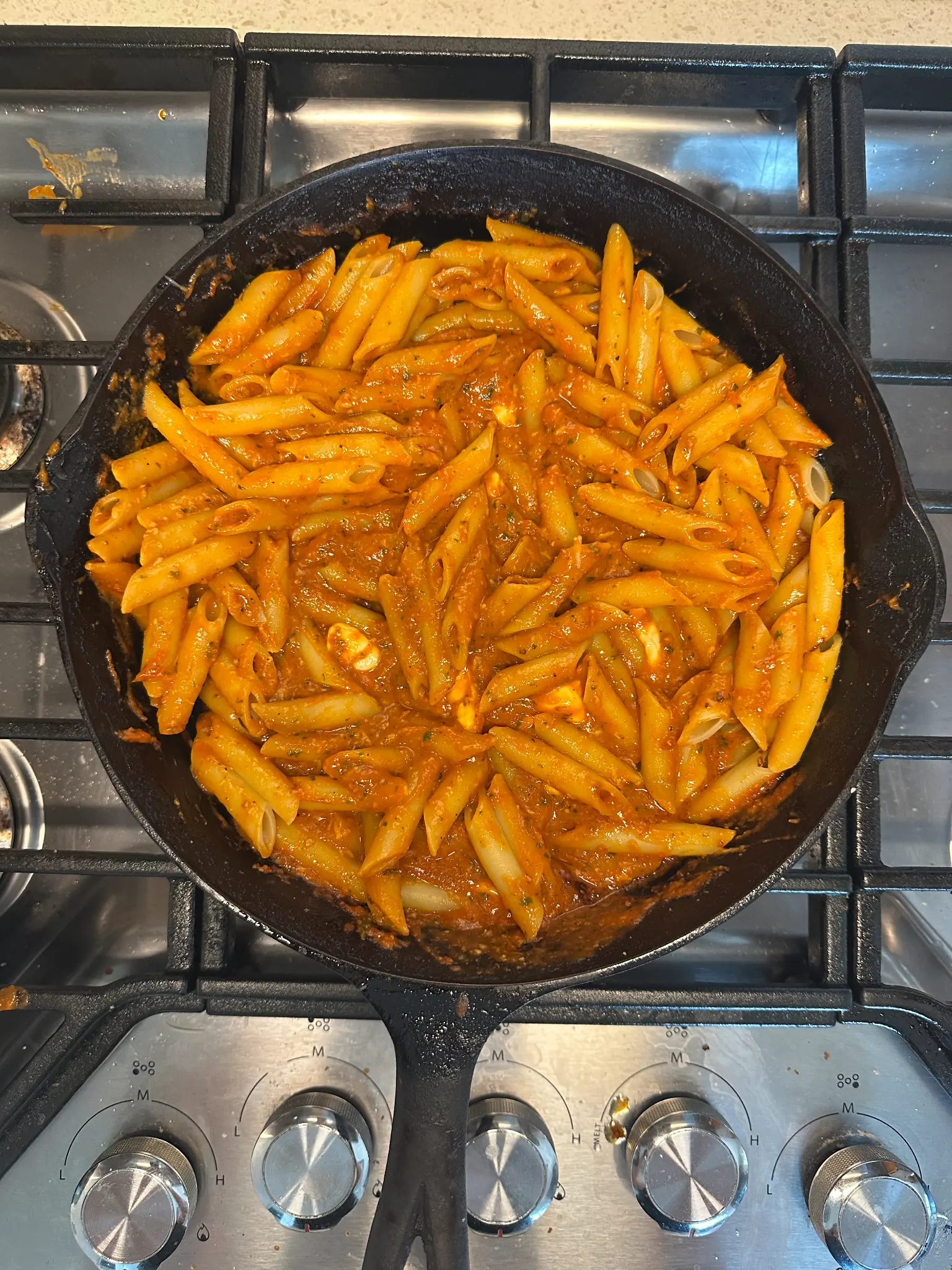 Mostaccioli tossed in roasted tomato marinara sauce in the cast iron skillet on the gas stove