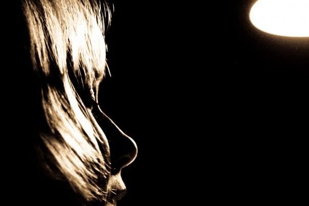Silhouette of a woman's profile against a dark background with a single light source