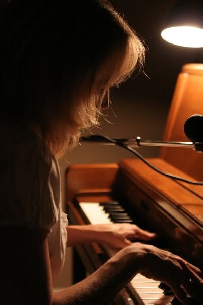 Kristen recording at the piano under a warm lamp