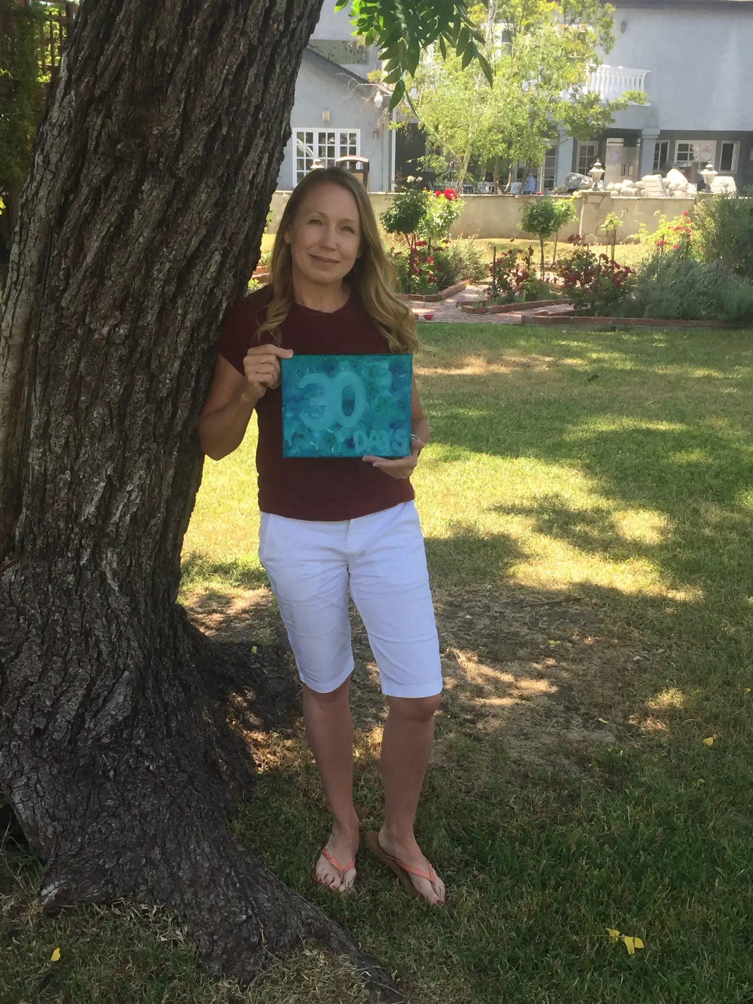 Kristen holding her 30-day chip in the garden at Harmony Place treatment center