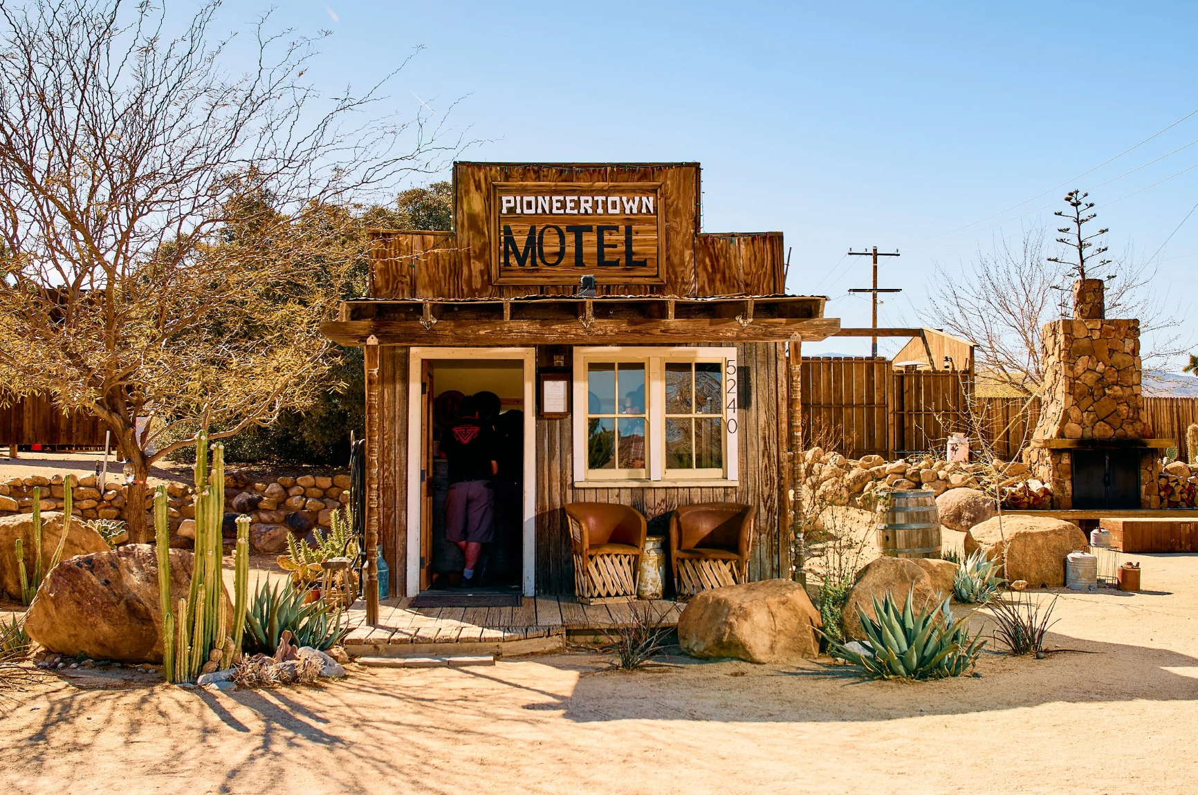 The Pioneertown Motel — a rustic Old West-style building with cactus and desert boulders out front